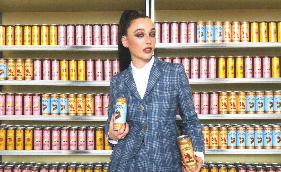 Emma Chamberlain standing in front of case with her coffee products