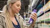 young woman reads nutrition label on dairy product in supermarket young woman reads nutrition label on dairy product in supermarket