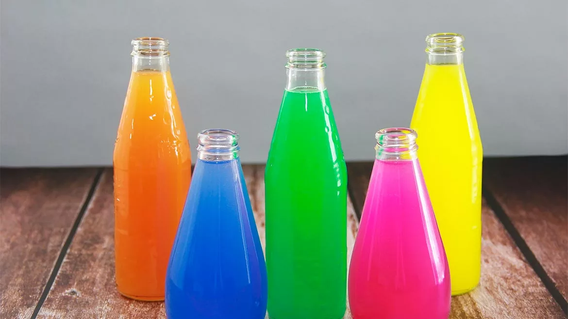 The image shows five glass bottles of basil seed drinks. 