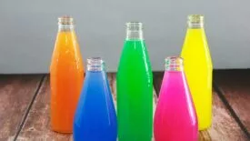 The image shows five glass bottles of basil seed drinks. 