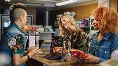This image appears to show a social moment in a small shop or cafe, with individuals conversing at a counter.
