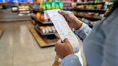 a person reviewing a long thermal paper receipt in a grocery store.