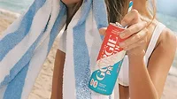 a person holding a can of Gorgie Protein Energy Drink in the Rocket Pop flavor next to a blue-and-white striped beach towel a person holding a can of Gorgie Protein Energy Drink in the Rocket Pop flavor next to a blue-and-white striped beach towel