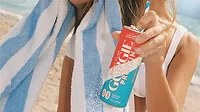 a person holding a can of Gorgie Protein Energy Drink in the Rocket Pop flavor next to a blue-and-white striped beach towel a person holding a can of Gorgie Protein Energy Drink in the Rocket Pop flavor next to a blue-and-white striped beach towel