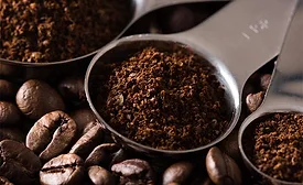 medium-to-dark roasted coffee beans alongside metal scoops filled with finely ground coffee