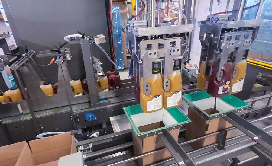 This image displays a high-speed automated tray packing machine used for packaging food or beverage products. 