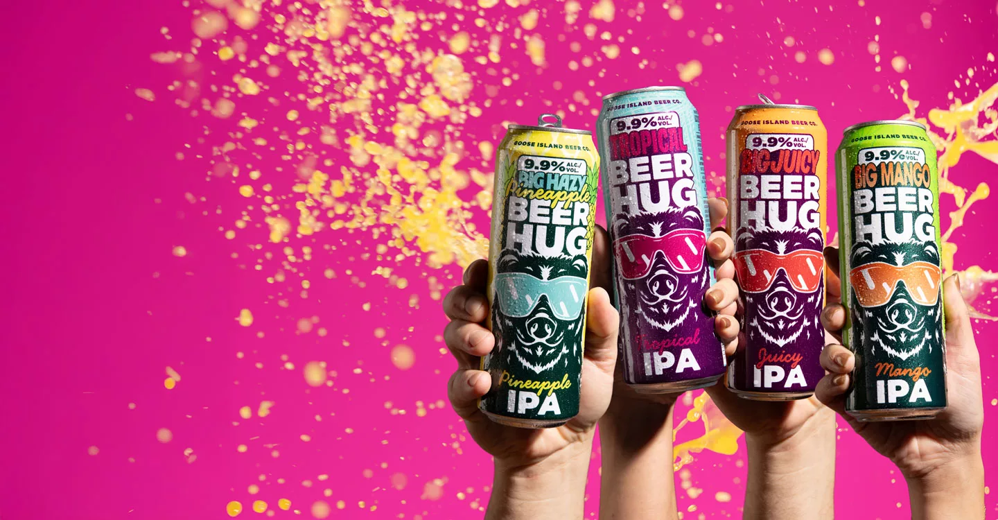 Hands holding cans of Goose Island Beer Co.'s Beer Hug IPA in Pineapple, Tropical, Juicy, and Mango flavors