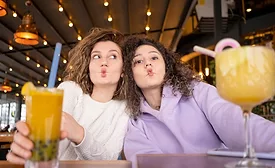 This image shows two people making a funny face while holding drinks in a restaurant or cafe setting