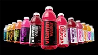 The image features various flavors of Vitaminwater, a brand of enhanced bottled water owned by The Coca-Cola Company.