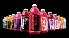 The image features various flavors of Vitaminwater, a brand of enhanced bottled water owned by The Coca-Cola Company.