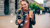 digital and mobile banking, showing a person using a smartphone surrounded by floating icons that represent online financial services