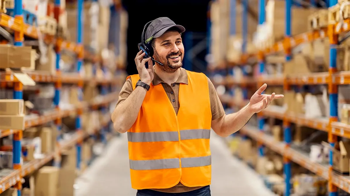 a person wearing a safety vest and a headset in what appears to be a warehouse setting a person wearing a safety vest and a headset in what appears to be a warehouse setting