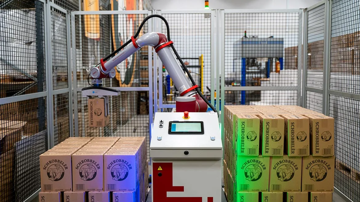 a collaborative robot arm (cobot) palletizing cardboard boxes in an industrial setting