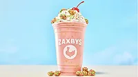 a pink Zaxby's cup with a handcrafted milkshake topped with whipped cream, colorful candy pieces, and a cherry a pink Zaxby's cup with a handcrafted milkshake topped with whipped cream, colorful candy pieces, and a cherry