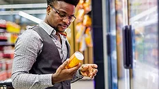 This image shows a man examining the label of a canned beverage in a store.