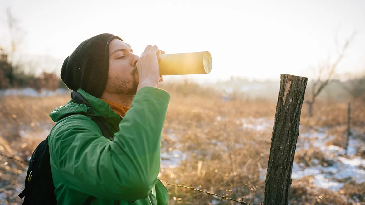 a person drinking from a reusable insulated water bottle 